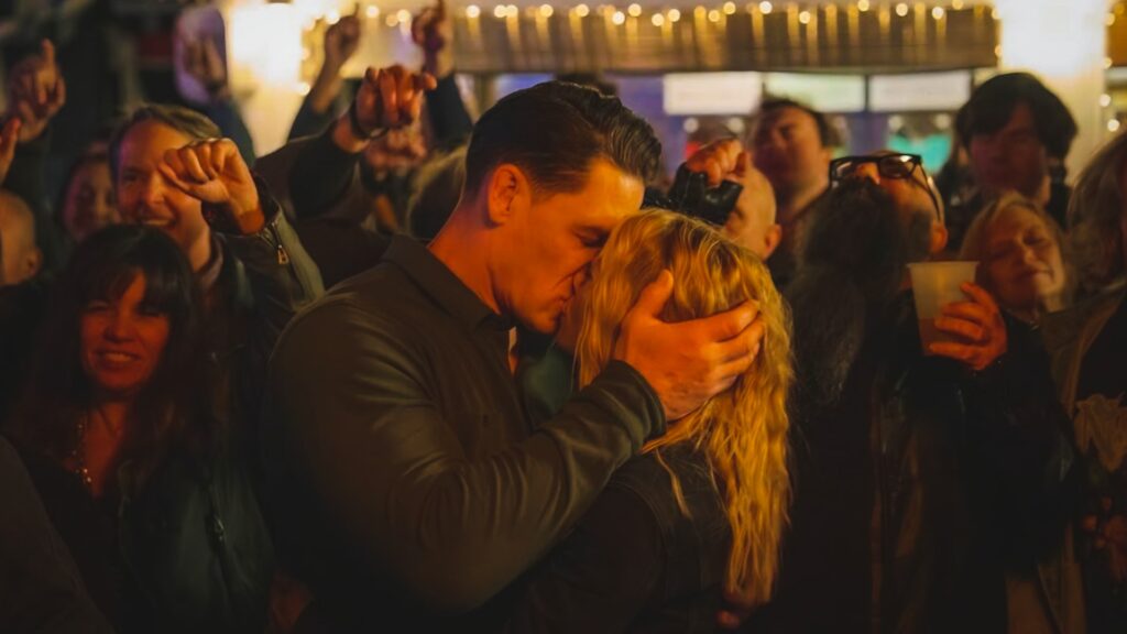 Jennifer Holland as Emilia Harcourt and John Cena as Peacemaker in Peacemaker Season 2 finale. Image © DC Studios / Warner Bros. Pictures. Fun fact: Holland is actually James Gunn’s wife.